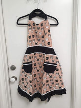 Load image into Gallery viewer, Pink and black colored kitchen apron hanging from a black hanger, hanging from a white door