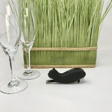 Load image into Gallery viewer, Picture of a black cat-themed bottle opener with two champagne glasses in front of it and green artificial grass to the side of it