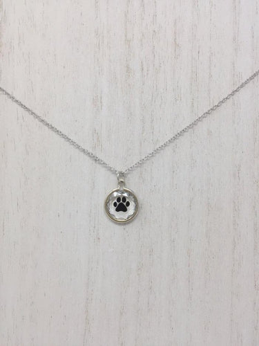 Picture of a sterling silver necklace with a circular pendant and a black paw inside of the pendant